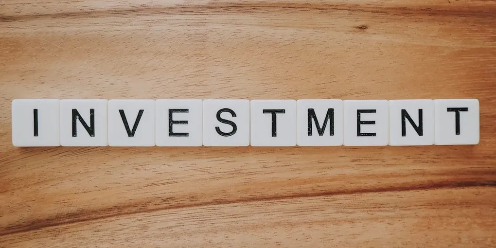 나무 탁자 위에 INVESTMENT라고 적힌 글자 블록