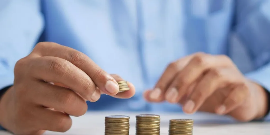 A person stacking coins into three small columns