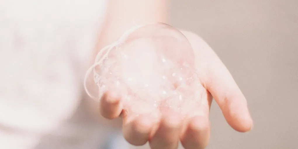 Foamy soap bubbles cupped in a hand, illustrating a gentle cleanser lather
