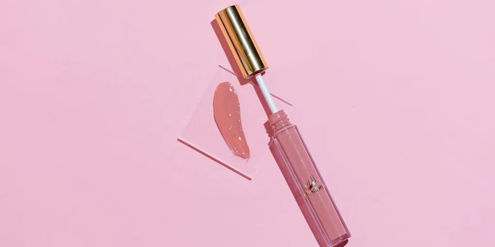 A pink lip gloss tube next to a glossy pink swatch on a pink background
