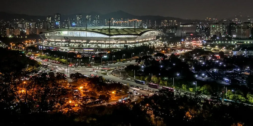 야간 조명이 켜진 축구 경기장과 주변 도심