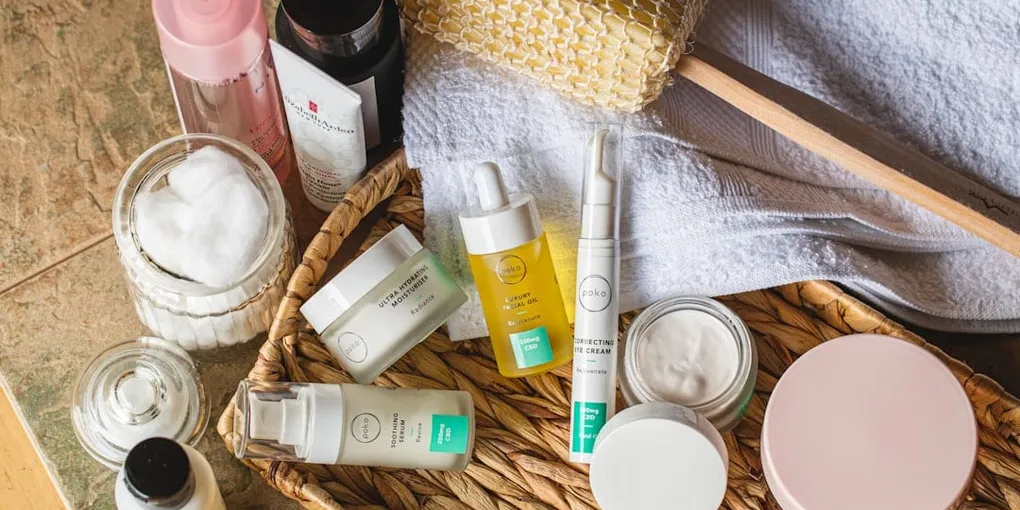 Skincare bottles, jars and cotton pads arranged on a bathroom shelf