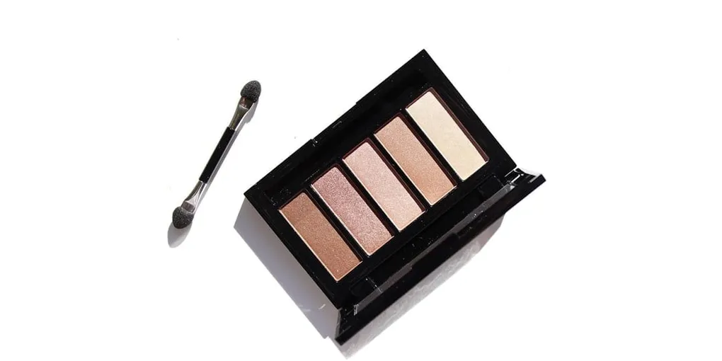 A brown and nude eyeshadow palette with a dual-sided makeup applicator brush on a white background.